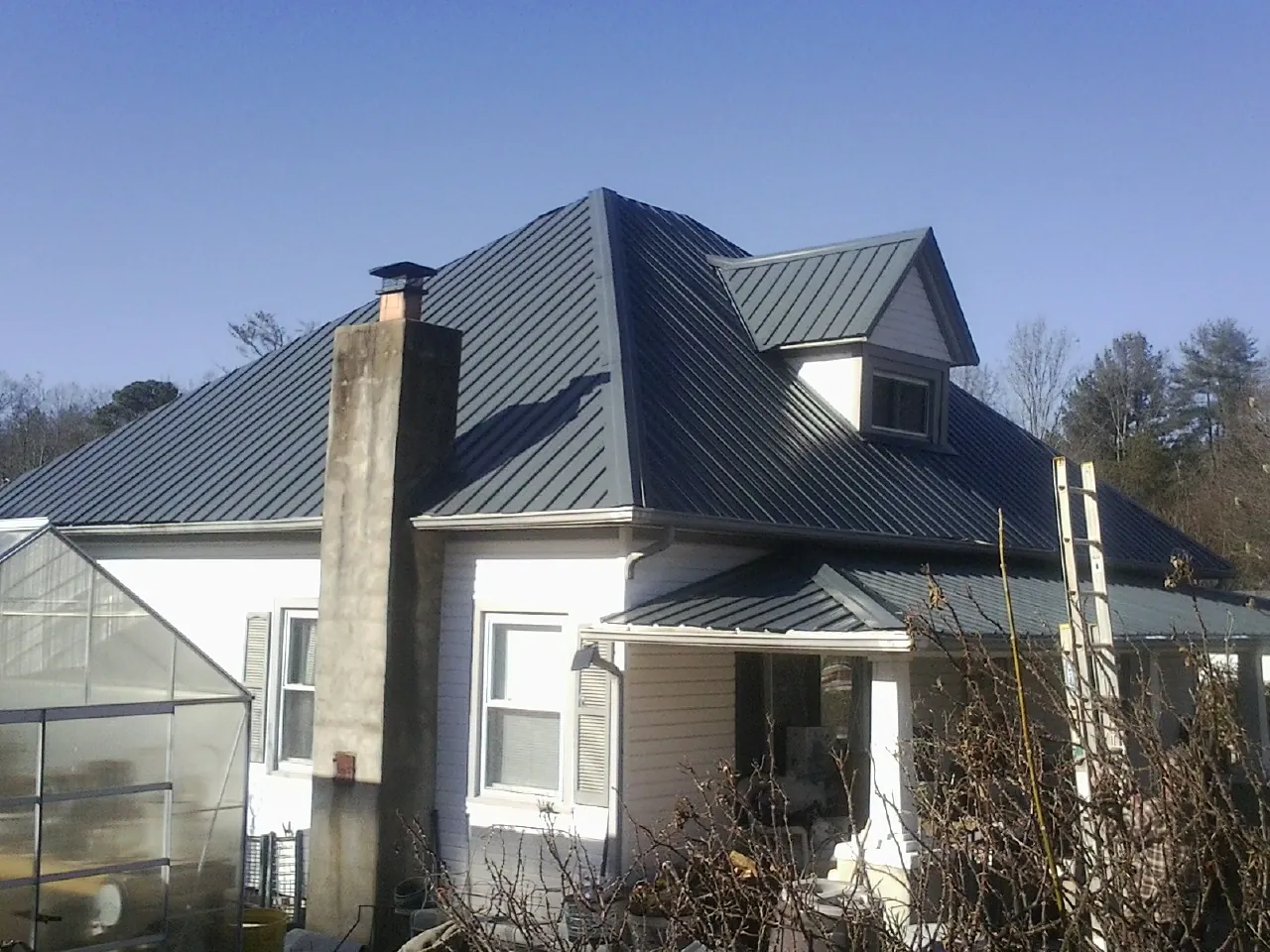 Dark blue standing seam metal roof on a white farmhouse with dormer — Slate & Tile Roof Repair by Roofing Brothers in Grants Pass