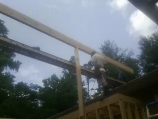 Carpenter setting a ridge beam over a new addition frame — Ice Dam Removal by Roofing Brothers in Grants Pass