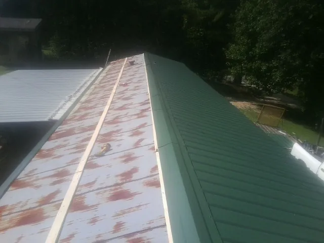 Old rusted panels beside newly installed green metal roofing — Wind Damage Roof Repair by Roofing Brothers in Grants Pass