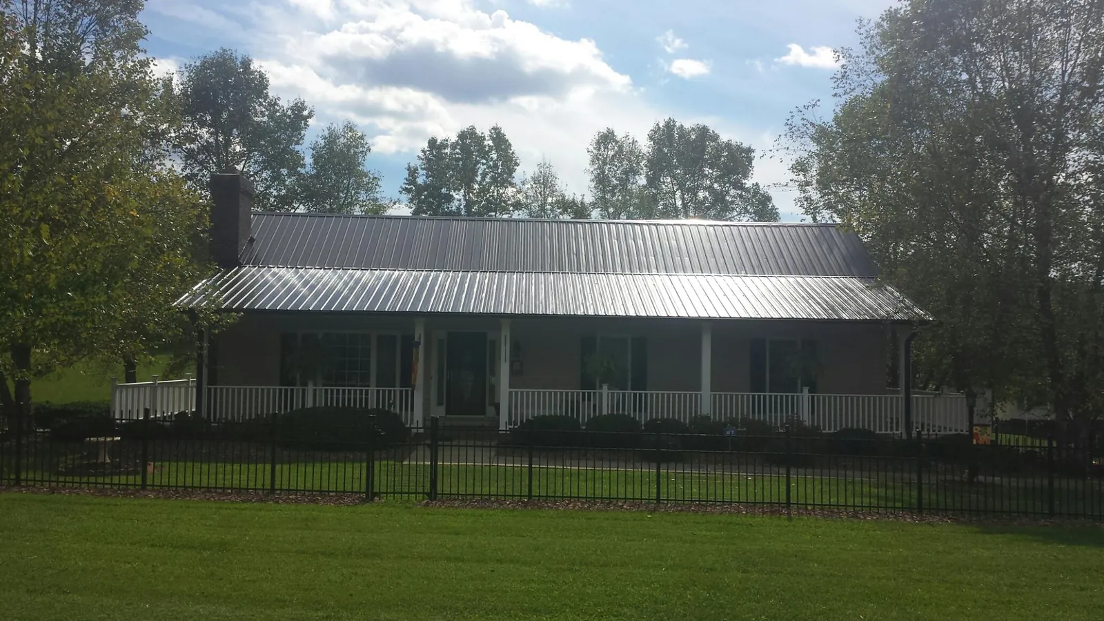 Gray metal roof on a brick ranch with a full width front porch — Gutter Guard Installation work by our crew in Grants Pass