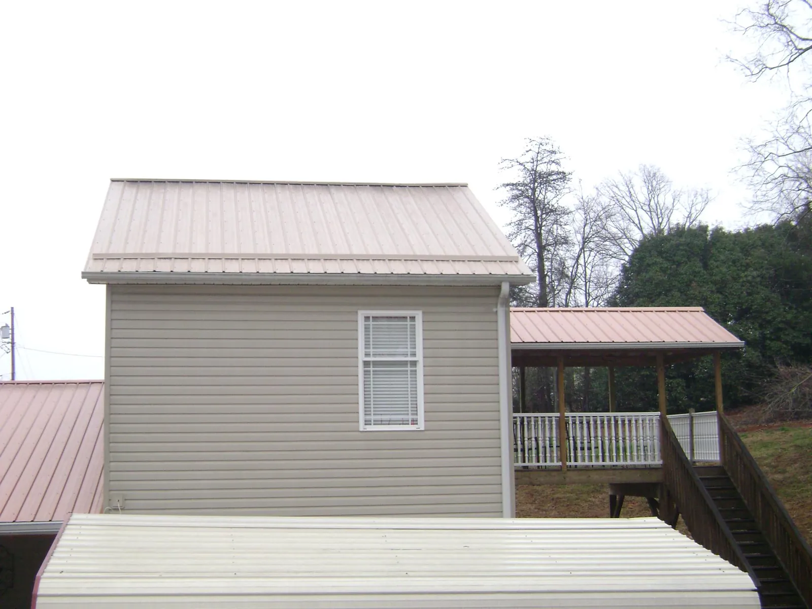 Tan metal roofs on a two story addition and attached porch, from a Roof Replacement job in Grants Pass